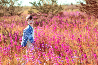 Happy boy in a field with bright flowers.