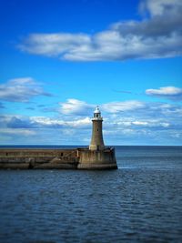 Lighthouse by sea against sky