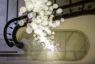 Low angle view of illuminated lighting equipment hanging on ceiling in building