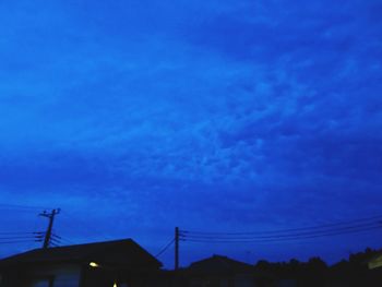 Low angle view of silhouette buildings against blue sky