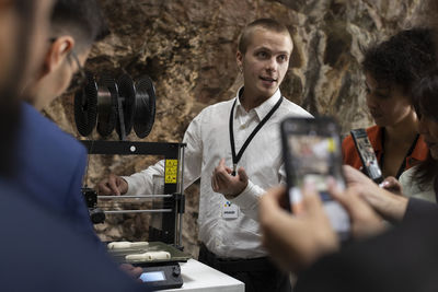 Businessman explaining 3d printer to colleagues during seminar at convention center