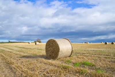 Hay bales on field against sky