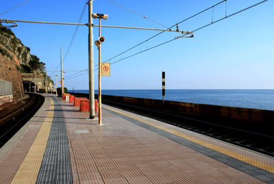 Railroad tracks by sea against clear sky