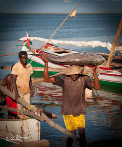 Men fishing at sea shore against sky