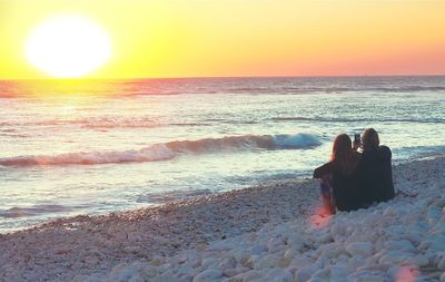 Rear view of women on beach during sunset