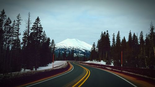 Empty road leading towards snowcapped mountain against sky