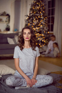 Young woman sitting in a room with a christmas tree with children