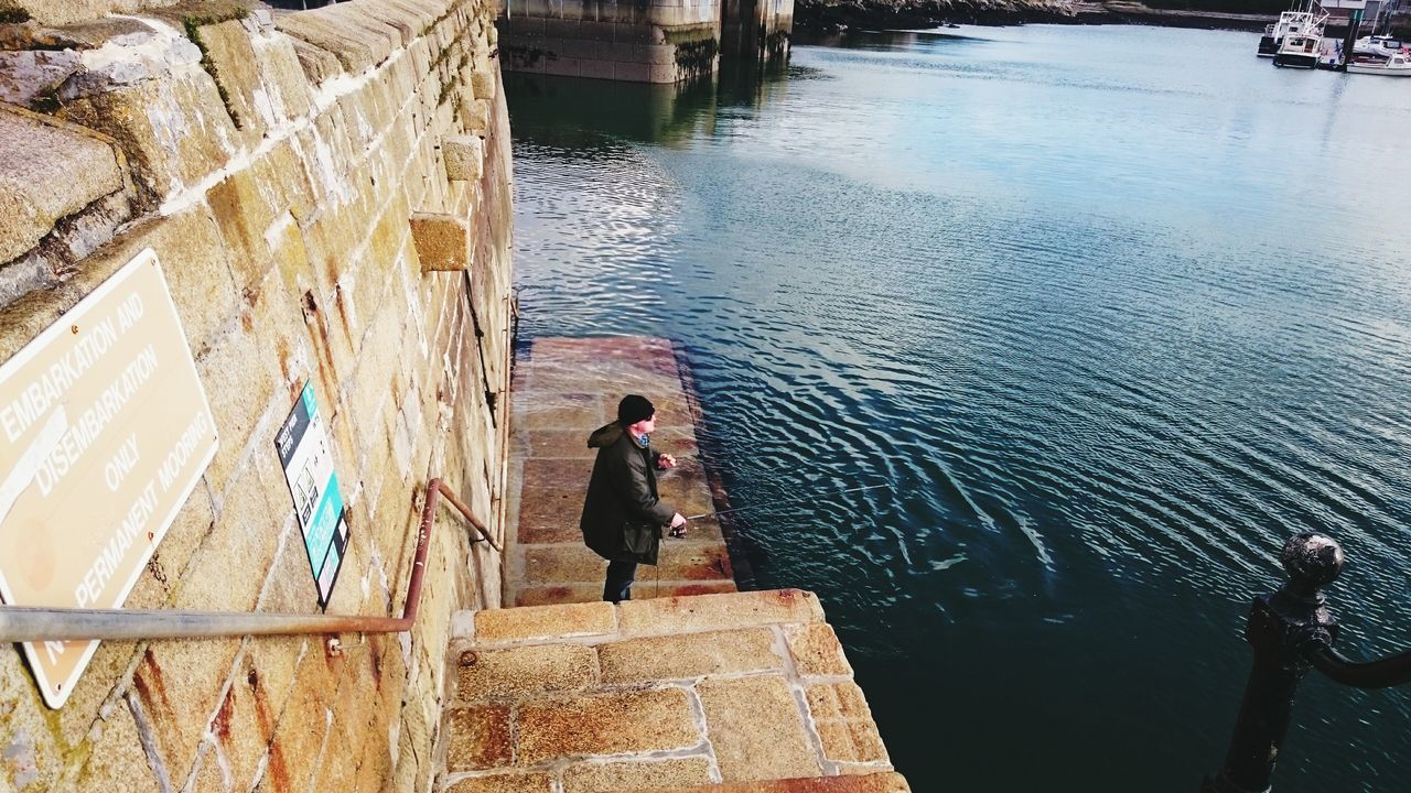 water, sea, lifestyles, leisure activity, high angle view, men, person, sitting, pier, full length, day, sunlight, steps, nautical vessel, standing, railing, outdoors, rear view