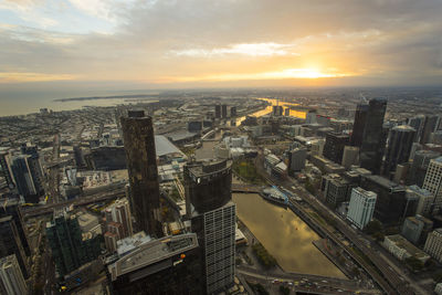 Aerial view of cityscape against cloudy sky during sunset