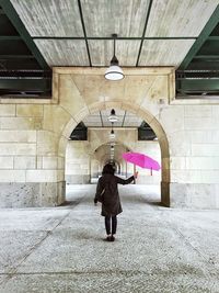 Full length rear view of woman standing by railing