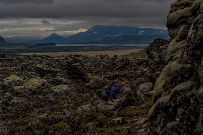 Two people hiking trough a volcanic field of magma in the highlands of iceland.