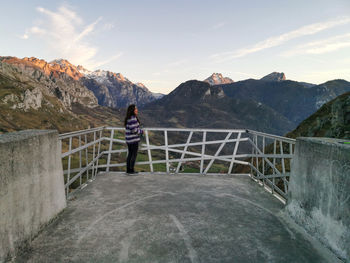 Rear view of woman standing on railing against mountains