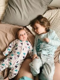 High angle view of a baby and her toddler sister laying on bed together and communicating 