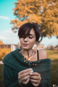 Portrait of young woman holding autumn leaves