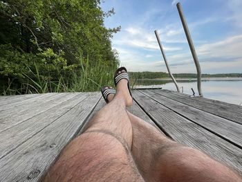Low section of man by tree against sky