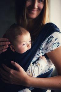 Smiling mother carrying baby at home