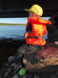 Boy sitting on rock by sea