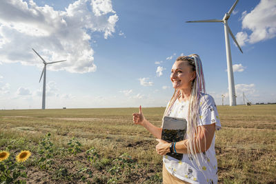 Blogger girl with bright braids shoots story about green energy,  wind energy, wind turbines