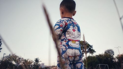 Rear view of child standing against clear sky