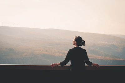 Rear view of woman standing on mountain against sky during sunset