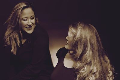 Close-up of mother and daughter against black background