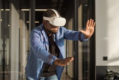 Black man in vr headset exploring metaverse world, touching virtual reality subjects. cyber world