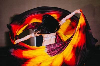 Blurred motion of woman dancing while holding dress performing on stage