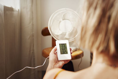 Woman holding thermostat at home