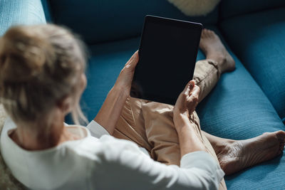 Woman using tablet pc on sofa at home