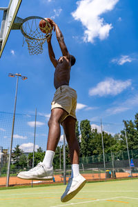 Young african american basketball player athlete in action jumping on artificial turf playing field
