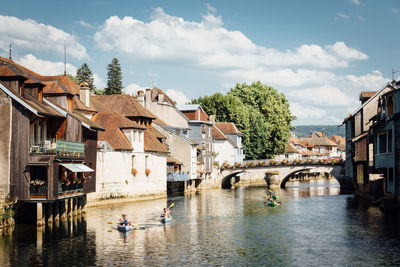 Arch bridge over river amidst buildings against sky