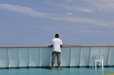 Rear view of man looking at sea against sky