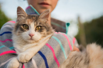 Close-up portrait of cat holding by girl outdoors