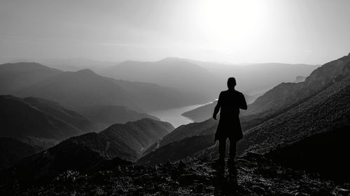 Silhouette man standing on mountain against sky during foggy weather