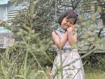 Shy girl standing against plants