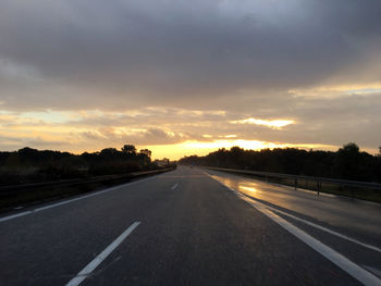 Empty country road along landscape at sunset