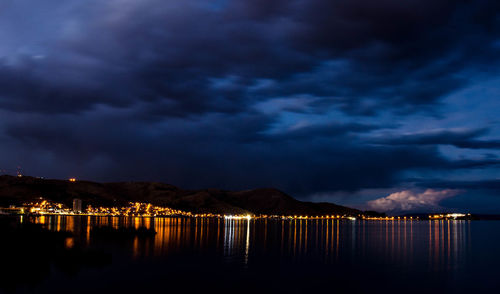 Scenic view of lake against cloudy sky at night