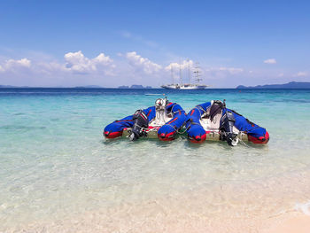 Boats moored in sea against blue sky