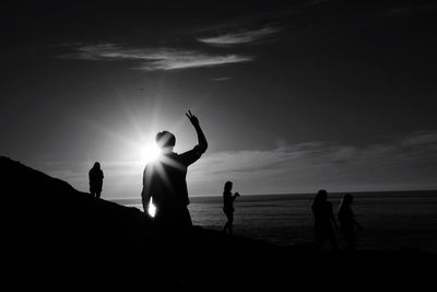 Silhouette people on beach against sky during sunset