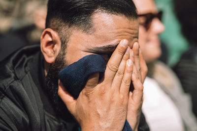 Headshot of despair man with head in hands at stadium stand on sunny day