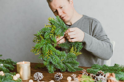 A man at home makes a christmas wreath from fresh spruce branches. decorating your home 