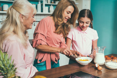Cheerful daughter with parents preparing food at kitchen