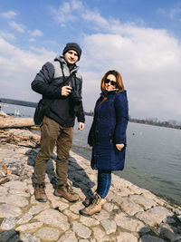 Full length of man and woman standing by sea against sky