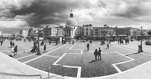 Group of people in city buildings against sky