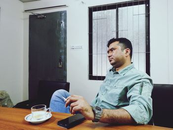 Man smoking cigarette while sitting at table