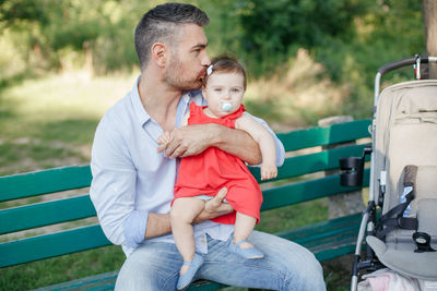 Caucasian proud father holding and kissing baby daughter. family dad and daughter walking together 