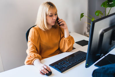 Young woman using laptop while sitting on table