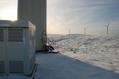 Traditional windmill by sea against sky during winter