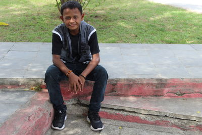 Portrait of young man standing on footpath