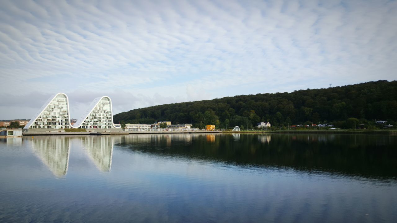 water, waterfront, architecture, built structure, reflection, lake, sky, building exterior, tranquil scene, tranquility, river, tree, scenics, cloud - sky, nature, mountain, cloud, day, beauty in nature, outdoors